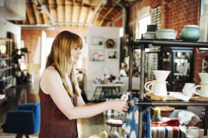 Woman standing in a shop, arranging merchandise on a shelf.,Retail Store,USA